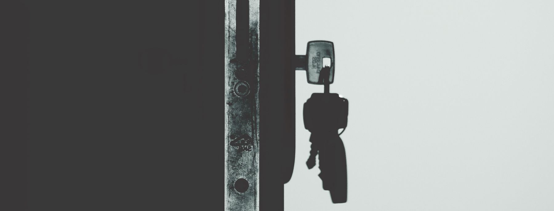 Black and white close-up of a key in a door lock
